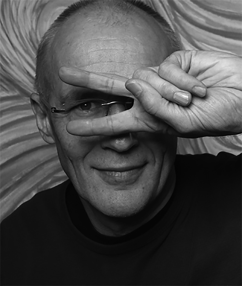S/W Foto von Rainer Geyer, wie er zwei Finger vor die Augen hält